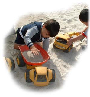 Children playing with trucks in the sand