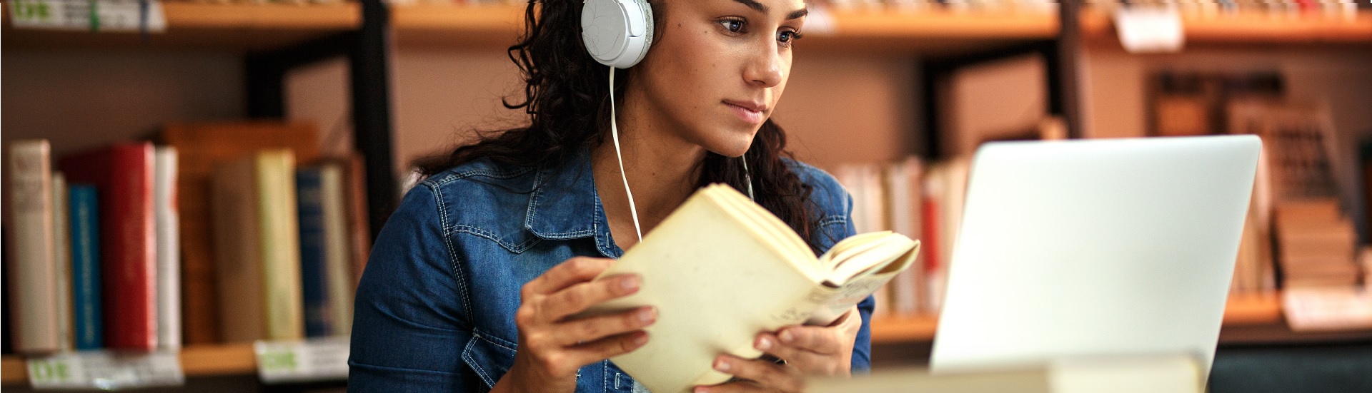 Woman with headphones with book and laptop