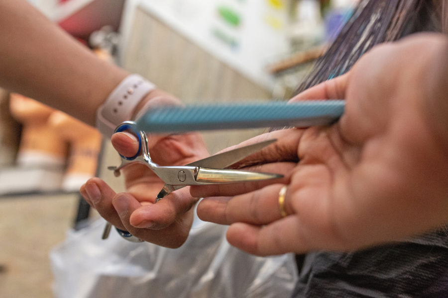 close-up of a cosmetology student cutting hair with scissors and a comb