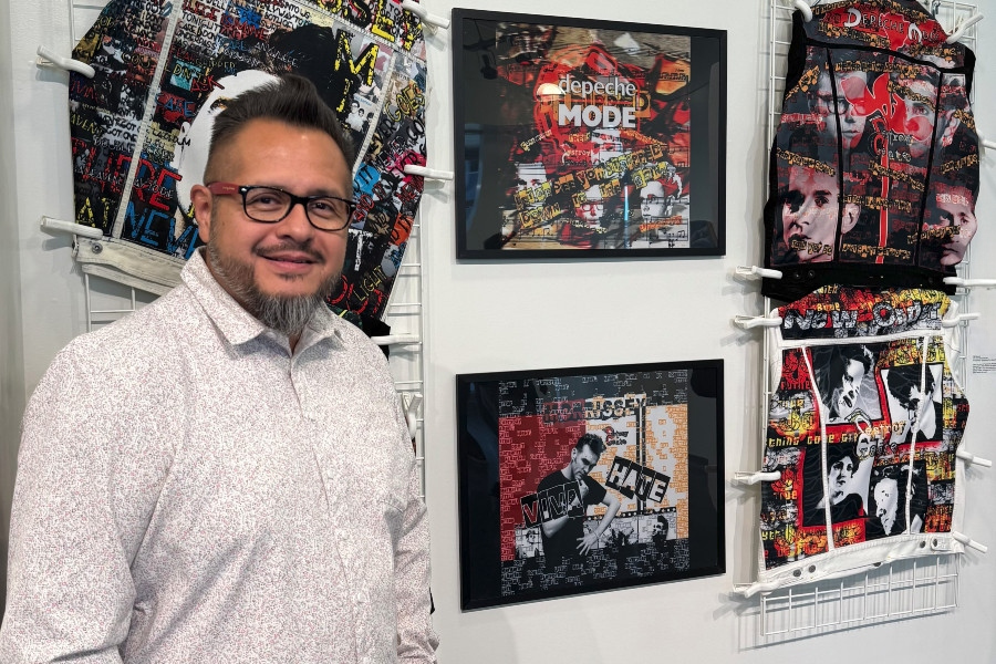 man standing beside artwork displayed in a college art gallery