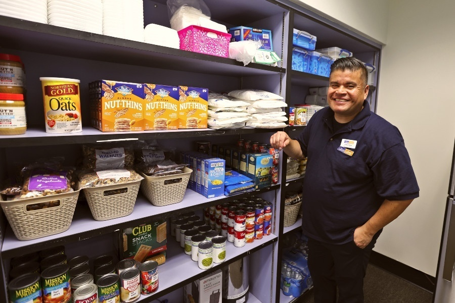 Jorge Razo standing beside shelves stocked with food and pantry supplies