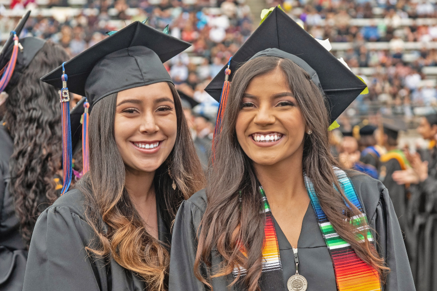 two smiling citrus college graduates wear caps, gowns and colorful stoles during commencement