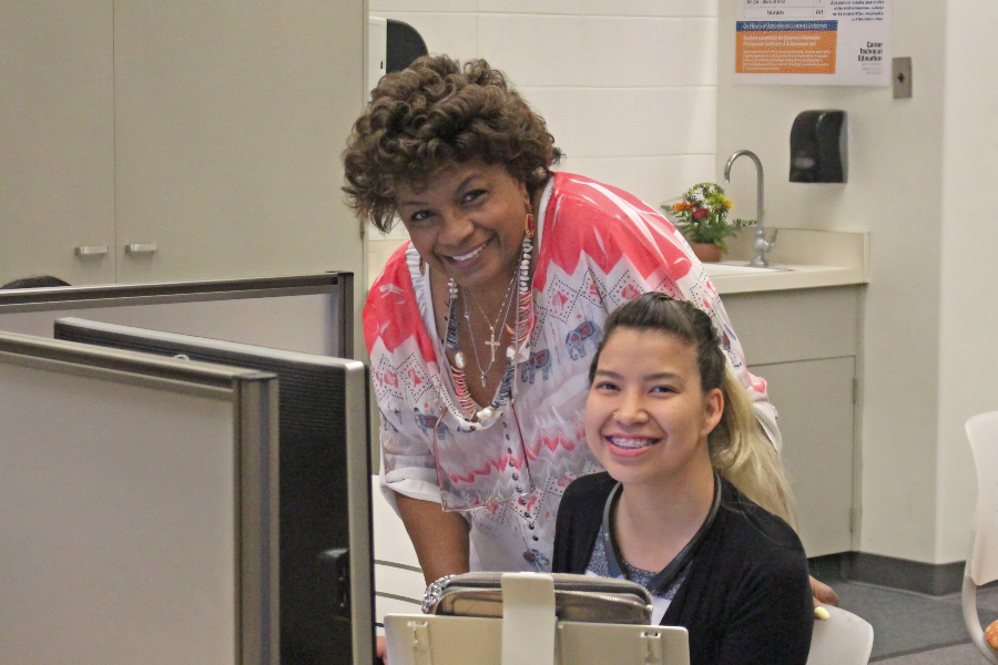 office technology instructor rhoda ann-michaux james assists a student working at a computer in a citrus college classroom