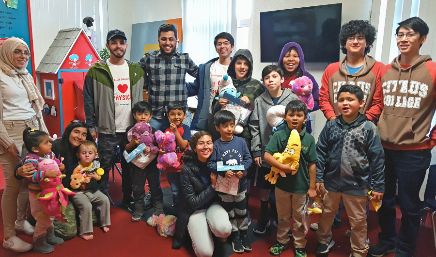citrus college rocket owls and children pose together holding stuffed animals and science kits during a community outreach visit