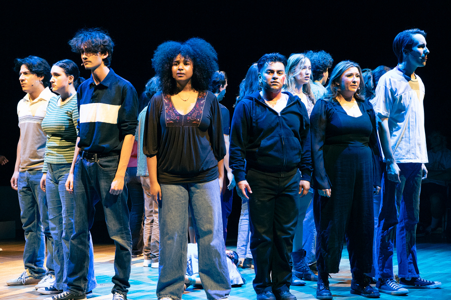 student performers standing on stage under blue lighting during a theatre production