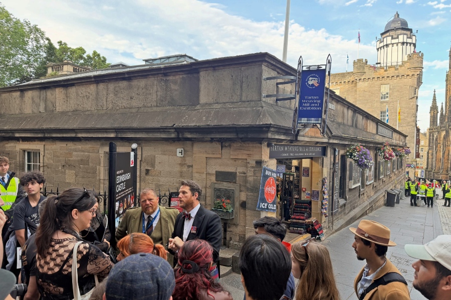 citrus college emerging theatre technologies students gather with guides near edinburgh castle on castlehill, surrounded by historic stone buildings and scottish shops