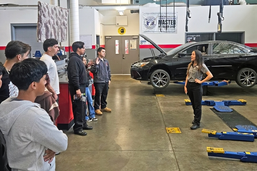 priscilla englert speaks with nogales high school students inside a citrus college automotive shop beside a vehicle raised on a lift