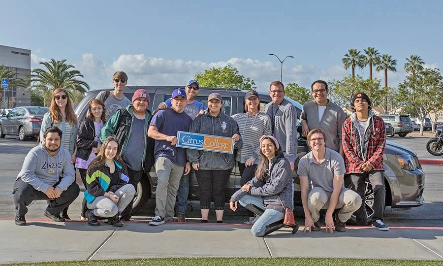 citrus college theatre arts students and faculty pose beside a van in a sunny parking lot while holding a citrus college sign