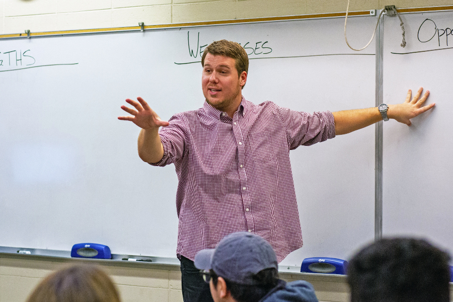 instructor gestures while teaching in front of a whiteboard during a real estate class