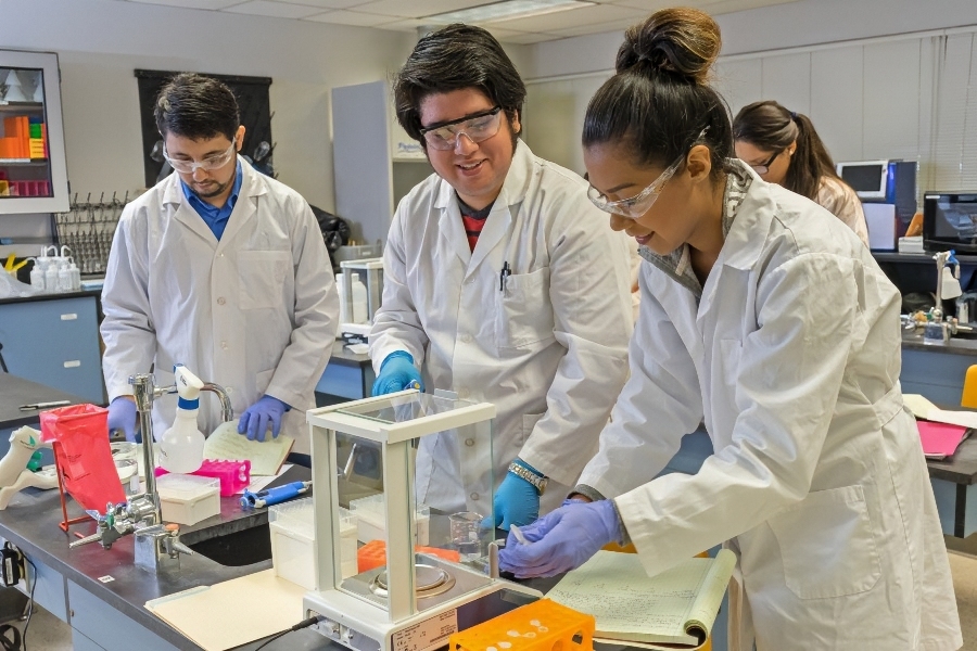 citrus college biotechnology students conduct laboratory work while wearing protective eyewear, gloves and lab coats.