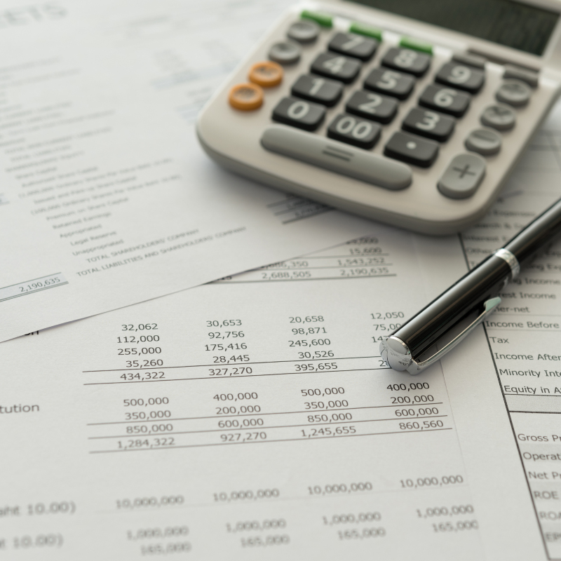 printouts of a detailed budget with a calculator and writing pen