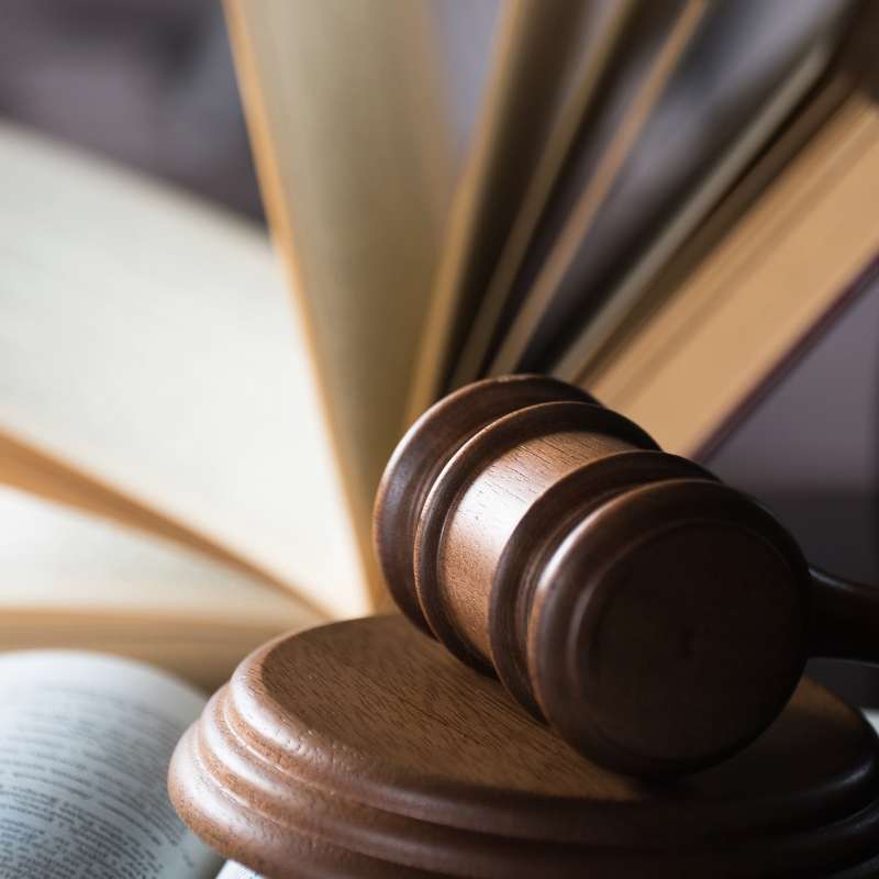 an open legal textbook and a wooden gavel sitting on a desk