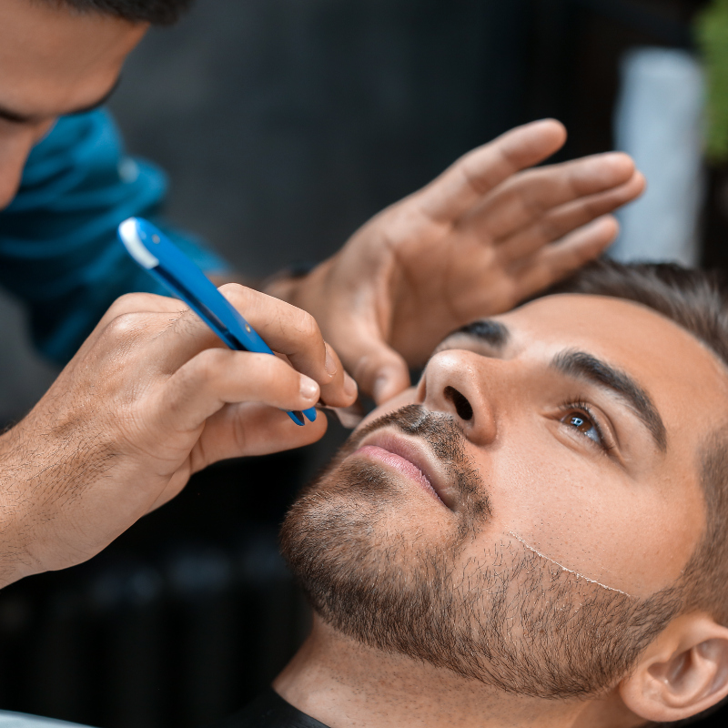 man receiving a beard trim and shave with a straight razor