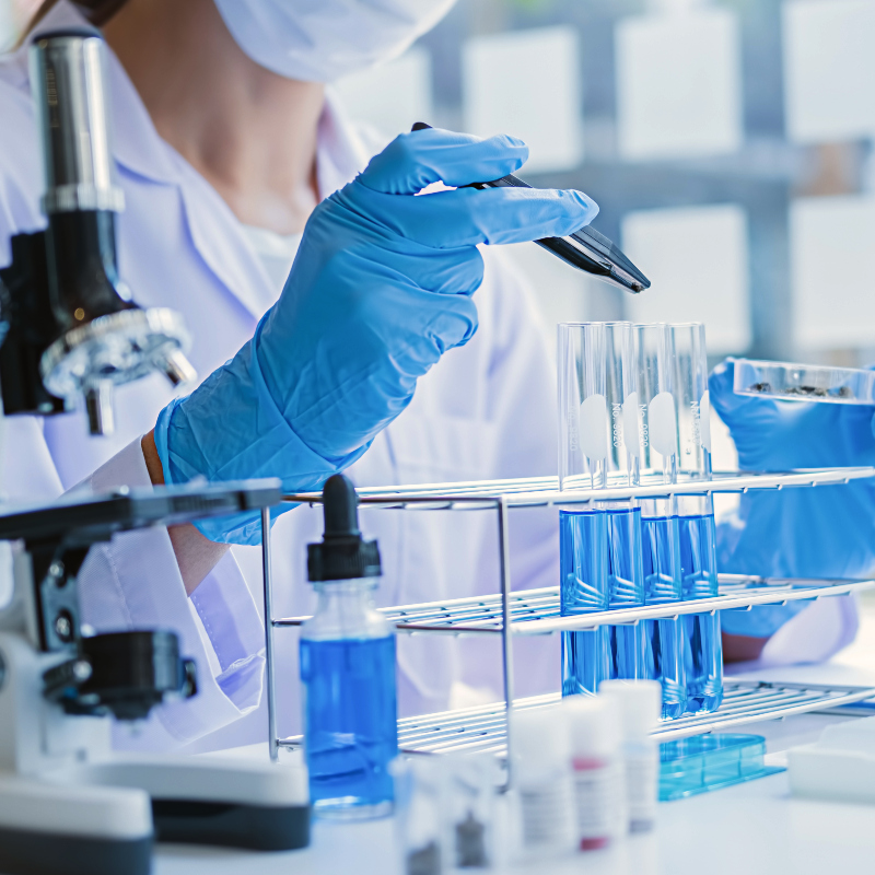female student in lab coat with a microscope, viles and other medical lab instruments
