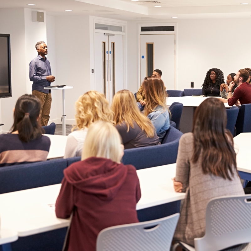 instructor presenting to adult learners during a workforce training or contract education class in a professional classroom setting