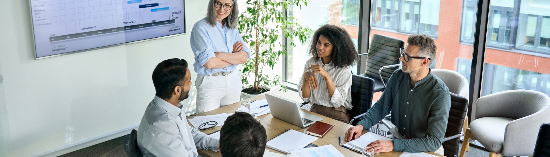 five people around a conference table in an office with a high rise view