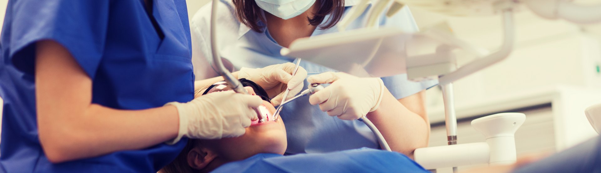 Dental assistants cleaning a child's teeth