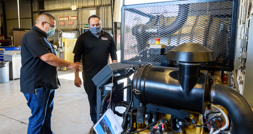 two people standing at a new power generator in the diesel tech building