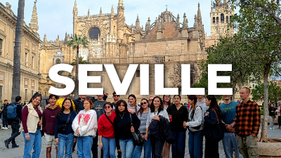 group of students posing in front of the ornate facade of seville cathedral in seville, spain, with the word "seville" displayed prominently across the center of the image