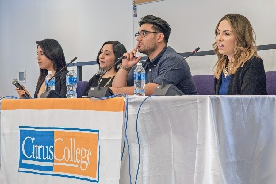 four speakers seated at a citrus college panel discussion with microphones