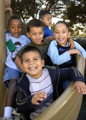a group of happy little boys crowdeed together on the new slide in the CDC play yard