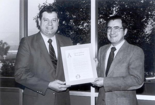 Dr. Zeleris with Dr. Geleris holding a proclamation from the college