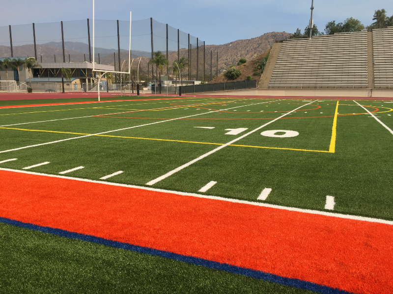 stadium turf, with the field house in the background