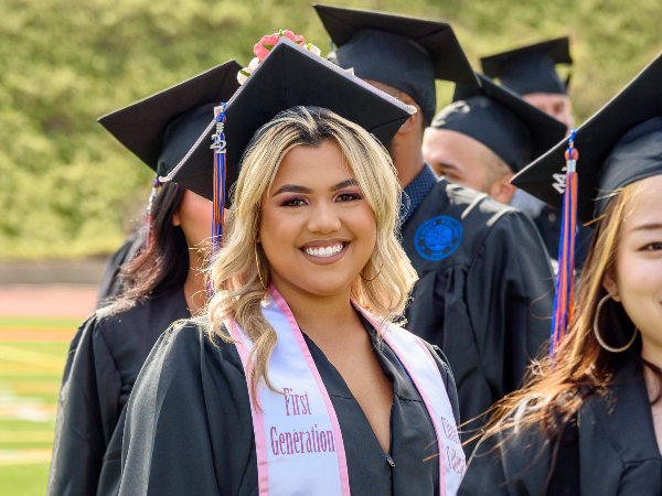 a proud and smiling first generation graduate at the commencement ceremony