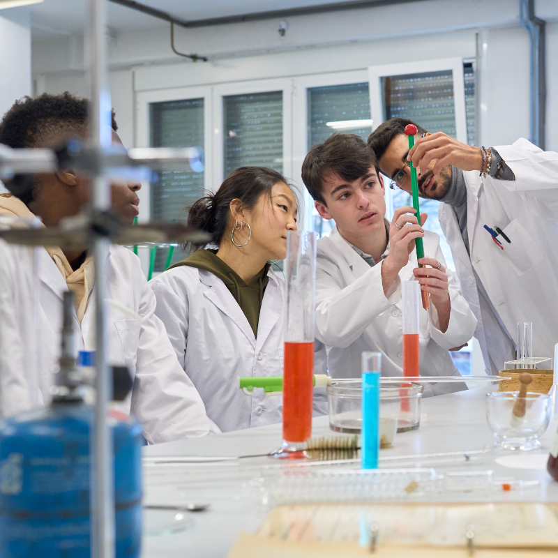 high school students in a chemistry college class being guided by the instructor