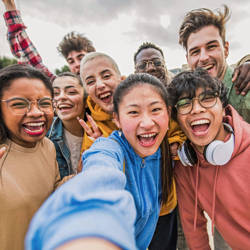 A diverse group of young college age students taking a selfie and looking joyful