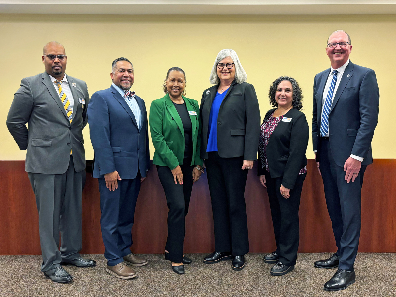 photo of the college board of trustees and superintendent/president standing in front of the dais in the administration building board room