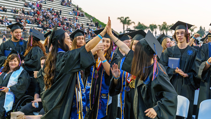 Citrus College grads celebrate with high fives after the ceremony