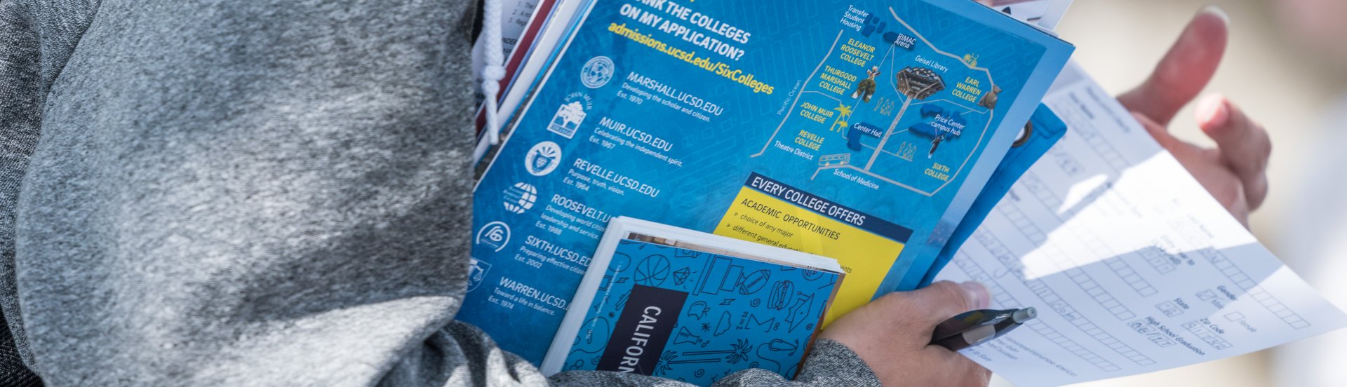 student holding a stack of brochures from the college transfer fair 