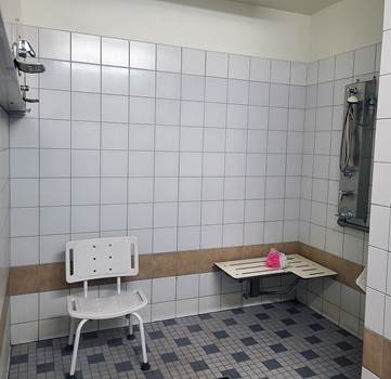 photo of accessible shower with chair and bench and handheld shower heads