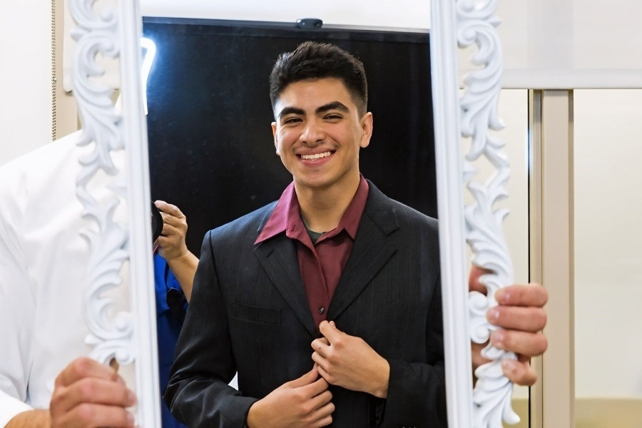 a student adjusts his suit while looking into an ornate mirror during the job prep pop-up
