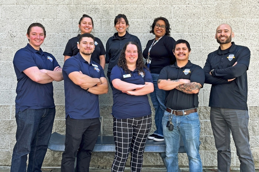 veterans success center team members posing together outdoors in front of a campus wall