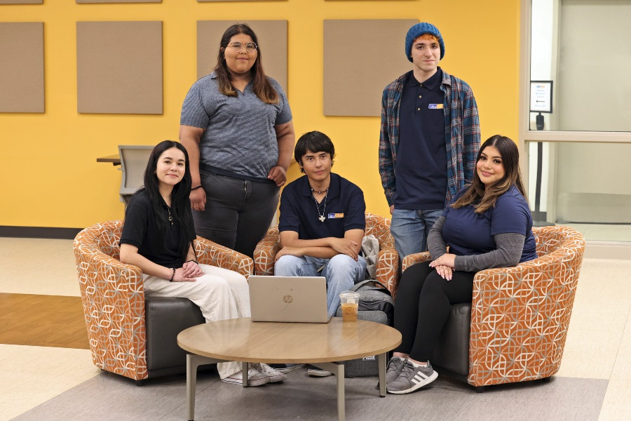 student ambassadors gathered in a campus lounge with a laptop on a table in front of them