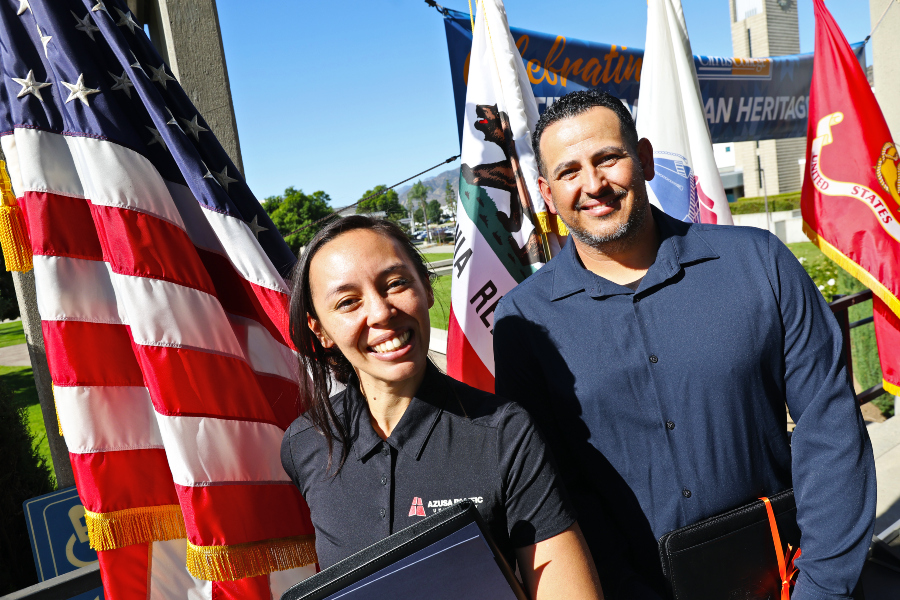 two veteran honorees stand in front of american, california and military service flags during the saluting our veterans ceremony