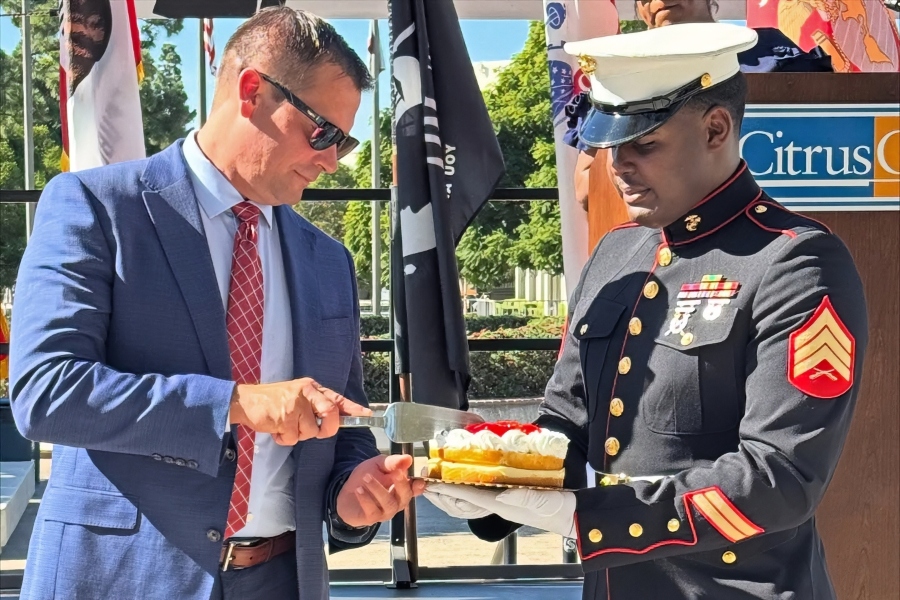a man in a blue suit cuts a cake held by a u.s. marine in dress uniform during citrus college's saluting our veterans ceremony