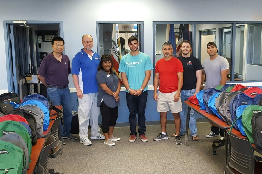 seven citrus college and foresters volunteers stand among rows of backpacks filled with school supplies for student veterans