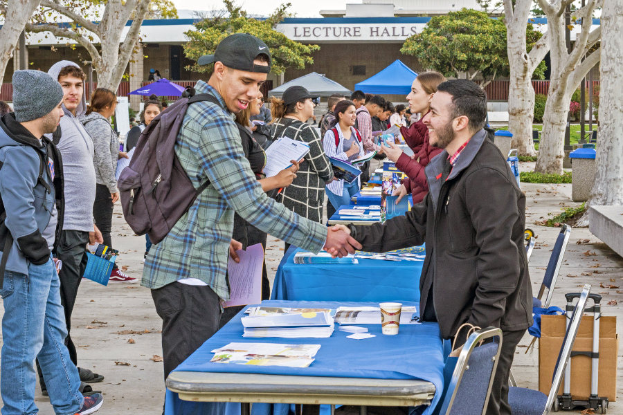 students gather at campus center mall tables to speak with university representatives during the citrus college spring transfer fair