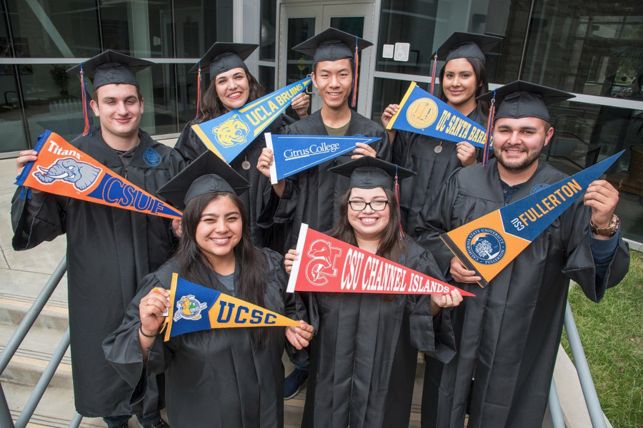 seven citrus college graduates in caps and gowns hold pennants representing ucla, uc santa barbara, uc santa cruz, cal state fullerton and cal state channel islands transfer destinations