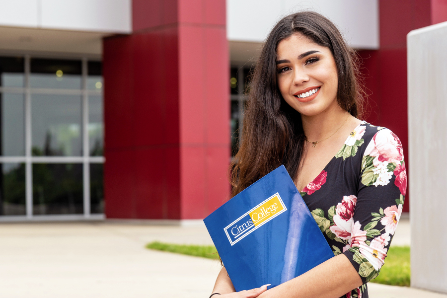 Latina student standing at the entrance of the college's Student Services Building