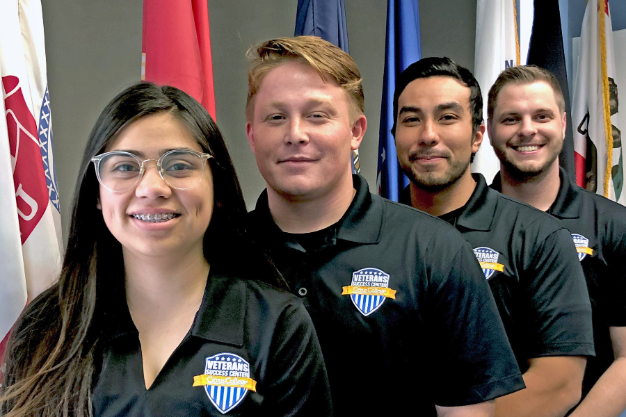 four citrus college veterans success center students stand together in matching shirts in front of military and state flags