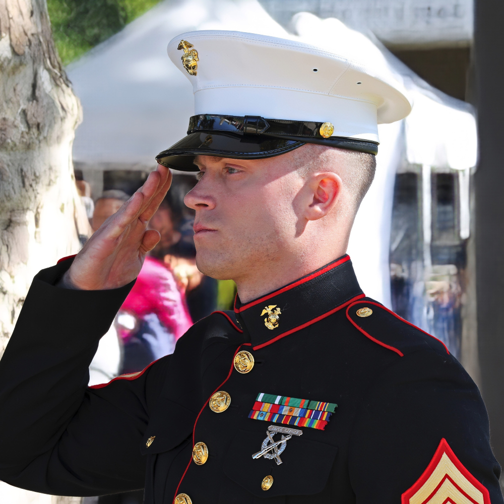 a u.s. marine in dress uniform salutes during an outdoor ceremony