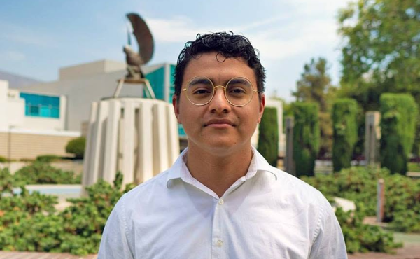 Marco Gudino standing in front of the owl fountain on campus