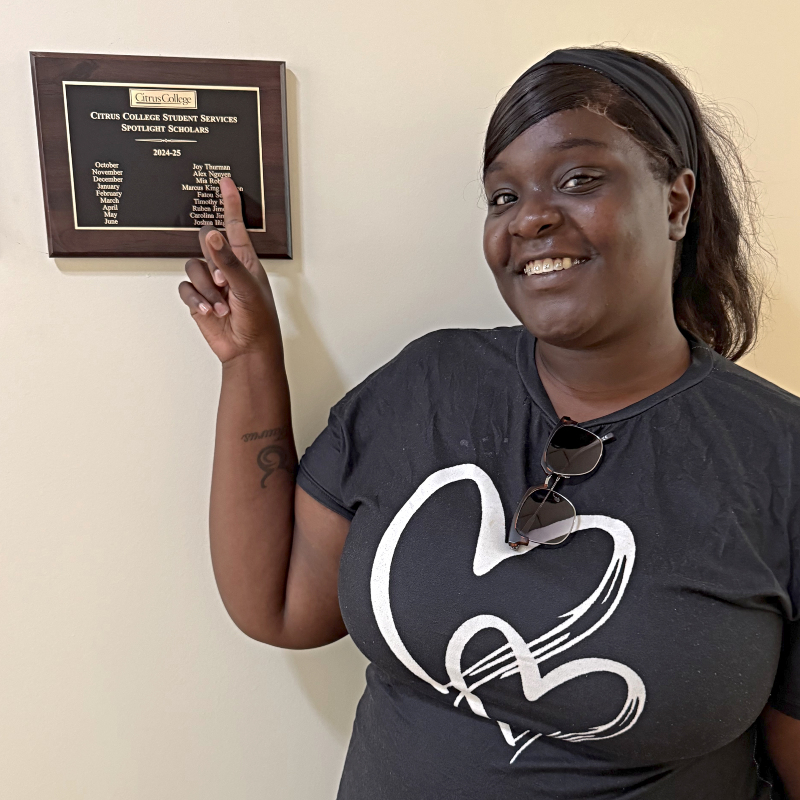 Joy Thurman pointing to her name engraved on a student services 