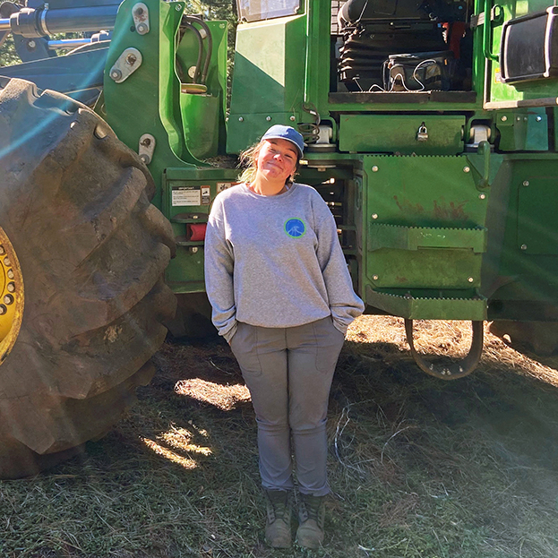 Makena Plourde standing next to a large piece of heavy equipment